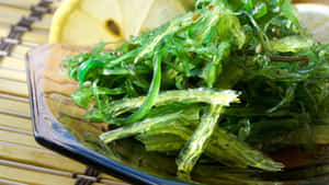 在竹蓆上與檸檬片一起閃閃發光的綠色海藻沙拉。 — 自然風景動圖 壁紙