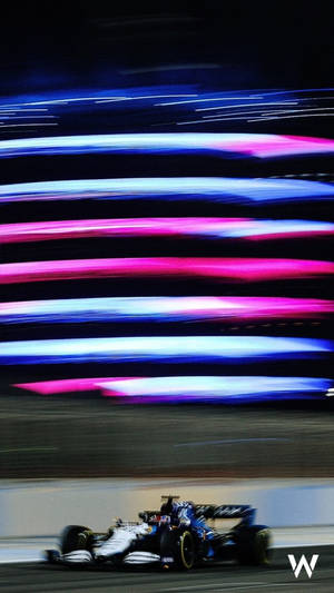 一級方程式賽車在夜間高速行駛，帶有霓虹燈光條紋。 — 運動 壁紙