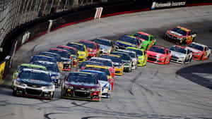日落時分，NASCAR賽車在高速過彎時緊密擠在一起。 — 賽車 壁紙