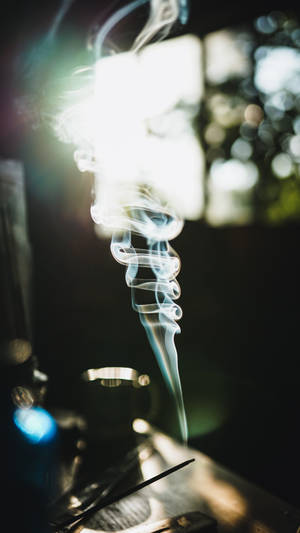 在黑暗背景下，柔和光線照亮的一縷旋轉煙霧痕跡。 — 抽菸 壁紙