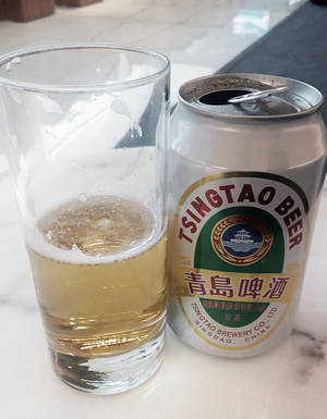 冰涼青島啤酒罐和玻璃杯放在大理石檯面上。 — 啤酒 壁紙