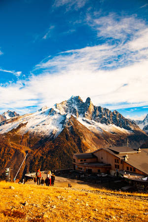 人們在日落時分從金色山坡上欣賞雪山山脈。 — 丘陵景觀 壁紙