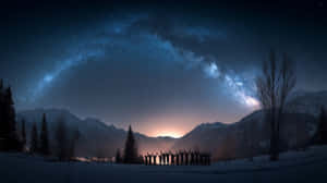 剪影人物在雪地上舉起雙臂，背景是星空、山脈和銀河 — 山脈 壁紙