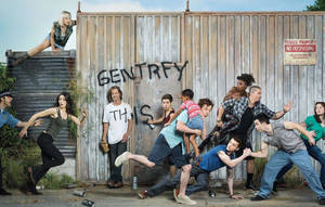 一群人在寫有 'GENTRIFY THIS' 的塗鴉牆前戲劇性地擺姿勢。 — 演員 壁紙