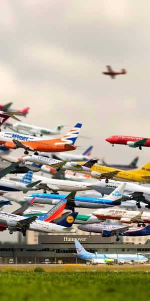 多架飛機在機場航廈上空編隊飛行，下方有綠色草地。 — 18:9 壁紙