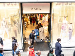 購物者進出Zara服裝店，櫥窗內有人體模型展示。 — Zara 壁紙