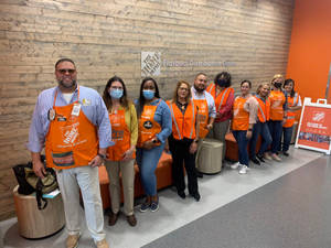 Home Depot員工穿著橙色圍裙在配送中心室內一起合影。 — 好市多 壁紙