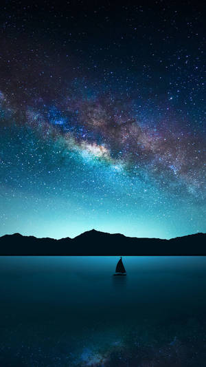 夜晚銀河下的帆船，背景有山脈 — 三星Galaxy 壁紙