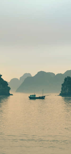 一艘小船漂浮在平靜的水面上，背景是霧濛濛的喀斯特島嶼。 — 海洋桌面 壁紙