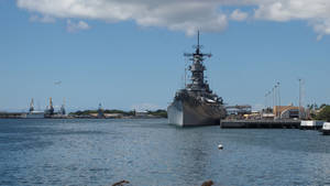 灰色戰艦停泊在碼頭，水面平靜，天空湛藍 — 海軍藍 壁紙