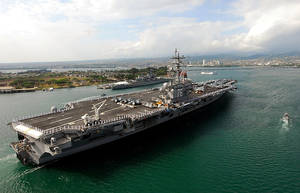 一艘大型航空母艦在沿海城市附近的海洋中航行。 — 珍珠港 壁紙