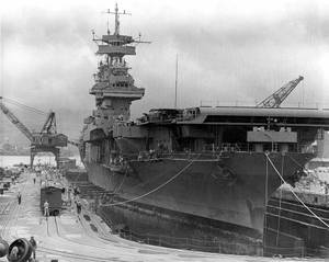 一艘大型航空母艦在造船廠建造中，有工人和起重機。 — 珍珠港 壁紙