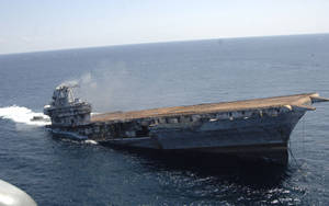 生鏽的航空母艦在海洋中下沉並冒煙 — 幽靈船 壁紙