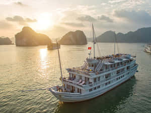 白色郵輪在日落時分航行於有喀斯特島嶼的海灣。 — 自然 壁紙