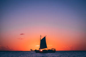 帆船上的人們在平靜的海面上欣賞日落。 — Chill 壁紙
