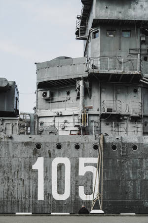一艘標有數字105的灰色大型軍艦在多雲的天空下停泊。 — 幽靈船 壁紙