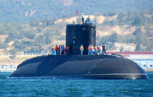 黑色潛艇，船員在甲板上，藍色海水，靠近丘陵 — 海軍藍 壁紙