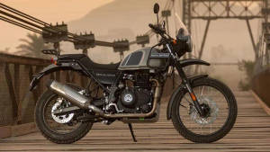 Royal Enfield Himalayan 摩托車在木橋上，背景有山脈和纜車。 — 腳踏車 GIF 壁紙
