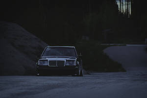 一輛深色 vintage Mercedes-Benz 在黃昏時停泊在森林附近的碎石路上。 — Mercedes Benz C300 壁紙