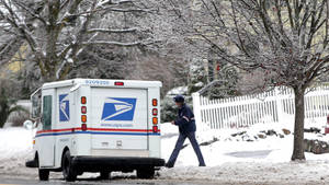 USPS郵政貨車停放在積雪街道上，郵差走過光禿禿的樹木。 — 卡車 壁紙