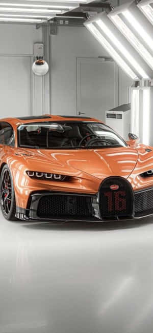 明亮白色車庫中的橙色Bugatti超跑，格柵上帶有發光的數字16。 — Galaxy Note 壁紙