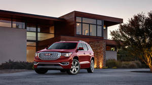 紅色GMC Acadia SUV停放在現代房屋前，黃昏時分。