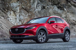 紅色Mazda CX-30 SUV停泊在岩石懸崖附近的碎石路上。 — 馬自達 壁紙