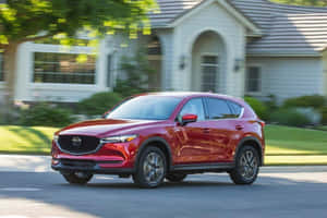紅色Mazda CX-5 SUV在白色房屋附近的郊區街道上行駛。 — 馬自達 壁紙