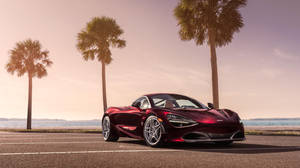 日落時分，紅色McLaren 720S跑車停泊在棕櫚樹和海洋附近。
