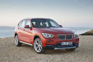 暮色中停在鵝卵石海灘上的紅色BMW X1 SUV。 — Mercedes Benz C300 壁紙