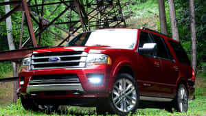 紅色福特 Expedition SUV 停放在生鏽金屬橋下的森林中。 — 福特 壁紙