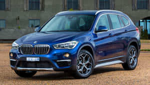 藍色BMW X1 SUV停放在建築物附近的碎石地上。 — Mercedes Benz C300 壁紙