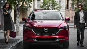 一輛紅色Mazda CX-5停放在城市街道上，有行人經過。 — 馬自達 壁紙