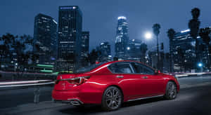 紅色轎車駛過充滿活力的夜晚城市，建築物和光跡閃爍。 — Acura 壁紙