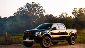 日落時分，黑色福特F-150皮卡車停在樹旁的碎石路上。 — 卡車 壁紙