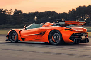 橙色Koenigsegg Jesko在日落時分的道路上飛馳 — 超跑 壁紙