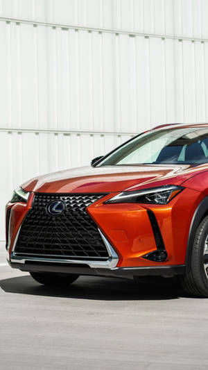 橙色Lexus SUV在白天停靠在白色波紋板牆旁。 — 汽車 iPhone 壁紙