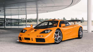 橙色McLaren F1超級跑車停放在現代玻璃天篷下。