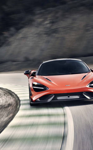 橙色McLaren跑車在蜿蜒的山路上飛馳。 — Infinix Xpad 30 Pro 壁紙