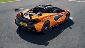橙色McLaren跑車在賽道上，帶有黑色飾件和大型尾翼。 — 酷炫F1 壁紙