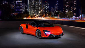 橙色McLaren跑車夜間停放在城市街道上，伴隨著發光的燈光和模糊的車流。 — 4K 法拉利 壁紙