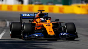 橙色和藍色一級方程式賽車在日落時分的賽道上疾馳。 — 酷炫F1 壁紙