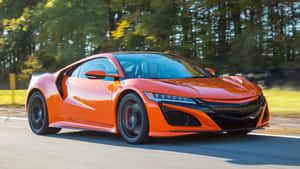 橙色跑車在道路上行駛，背景有樹木 — Acura 壁紙