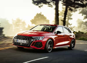 紅色 Audi RS3 Sportback 在陽光明媚的道路上行駛，背景有樹木。 — 日出 壁紙