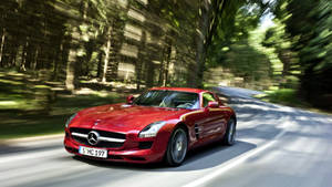 紅色 Mercedes 跑車在白天穿越森林道路疾馳。 — 好看汽車 壁紙