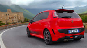 紅色Fiat Punto Evo ABARTH在山路上靠近石頭廢墟。 — 賽車 壁紙