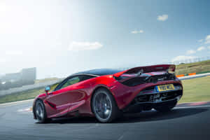 紅色McLaren賽車在晴朗天空下的賽道上飛馳。 — 麥拉倫 720S 壁紙