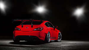 夜間在明亮聚光燈下帶有後擾流板的紅色跑車。 — AMOLED 壁紙