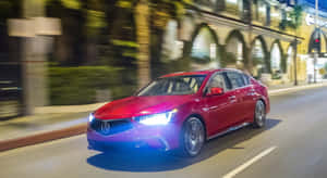 紅色轎車在夜間城市街道上快速行駛，帶有模糊的燈光和建築。 — 夜晚 壁紙