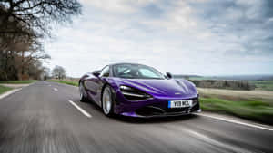 紫色McLaren 720S在鄉村道路上疾馳，背景模糊。 — Studio Display 壁紙